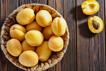 Ripe yellow apricots in bowl on a wooden table
