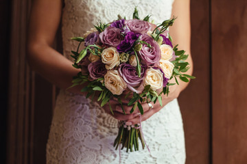 young beautiful bride in white dress holding wedding bouquet, bouquet of bride from rose cream spray, rose bush, rose purple Memory Lane, violet eustoma, eucalyptus .