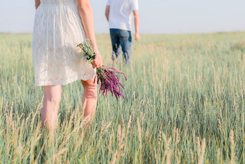 Cute young couple in love walking in a field of lavender flowers