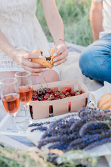 Couple in love are having summer picnic outdoors with wine, fruits and croissants
