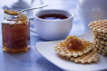 Breakfast. Fika. White cup of tea with thin waffles and lemon jam.