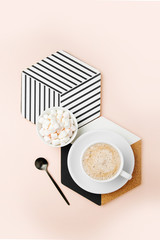 Breakfast with a cup of coffee with a geometric decor on pale pink background. Flat lay, top view