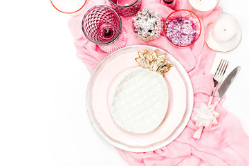 Wedding or festive table setting. Plates, wine glasses, candles and cutlery with  decorative textile on white background. Beautiful arrangement on pink color