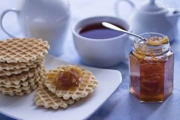 Breakfast. Fika. White cup of tea with thin waffles and lemon jam.