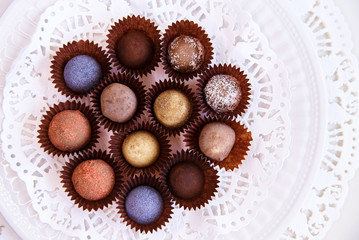 A set of color truffle candy on a white plate with lace.
