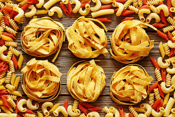 Tagliatelle nests and pasta on a wood background