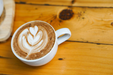 Beautiful Latte art coffee with foam milk tree picture, placed on the wooden table background.
