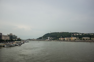 Naklejka premium Budapest waterfront in gray rainy day time with river and ships
