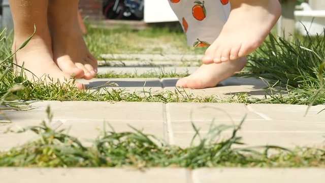 Barefoot little girls walk, run along the path. Little girls naked legs. Slow motion