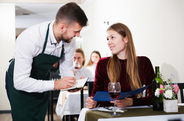 Cheerful woman is giving order to male waiter in luxury restaurante