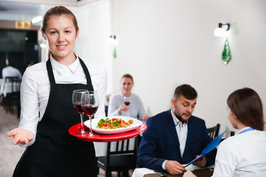 Portrait of welcoming female waiter who is standing in restaurante