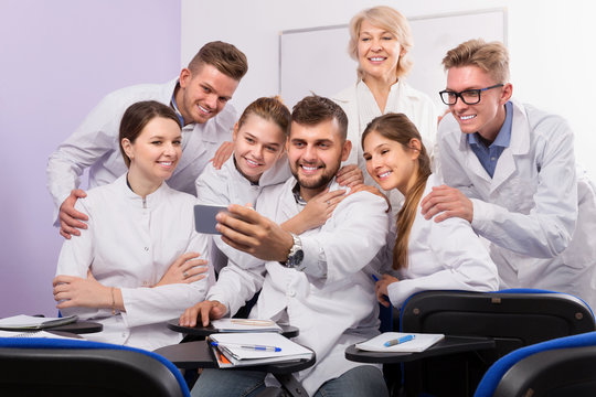 Smiling medical students and female professor taking selfie