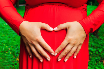 future mom shows the heart with her hands on her abdomen