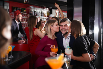 Guy getting friendly kiss by two girls in bar