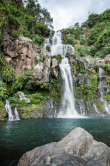 Fototapeta na wymiar Tropical Cascade Waterfall with Pool Basin in Green Nature and Swimming