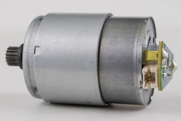 Small electric motor on a white workshop table. Electric drive used in small electrical devices.