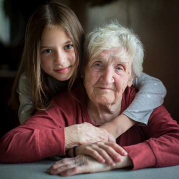 Portrait of an elderly woman with her little granddaughter. Old and young.