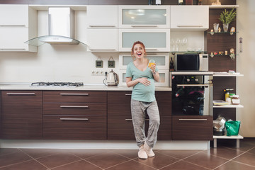 Happy loughing pregnat woman on the kitchen.