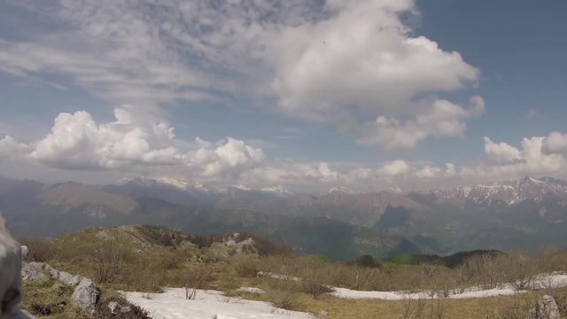 Time lapse (static) with unrecognizable people hiking and clouds moving upon mountain environment