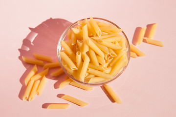 Top view of italian pasta in bowl on pink background, cooking concept