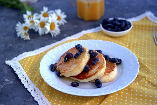 Oatmeal pancakes with honey and berries on a dark gray concrete background
