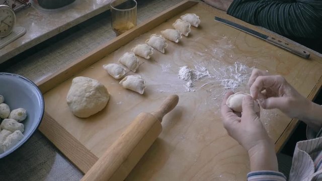 woman making traditional Polish dumplings , pierogi. They contain white cottage cheese with onions and mashed potatoes  .