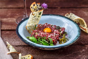 Delicious steak tartare with yolk, capers, green onion and bread