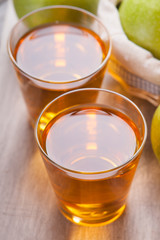 Apple juice in glasses and apples on wooden cutting table 