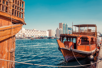 Naklejka premium Skyline view of Dubai Creek with traditional boats and piers. Sunny summer day. Famous tourist destination in UAE.