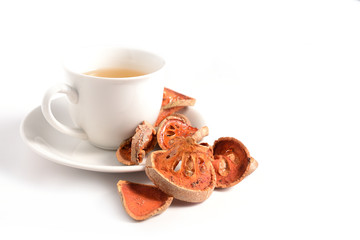 Slices of dry bael fruit and cup of dried bael juice on white background. (Aegle marmelos)