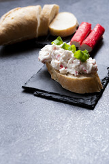 Appetizer with surimi sticks and mayonnaise served on a black slate tray. 