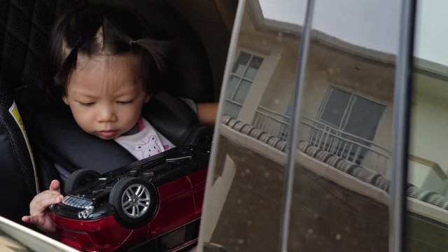 cute baby sitting on car seat playing small toy