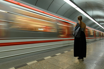 Subway station with standing young lady infront of train with motion blur
