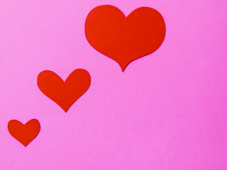 Red paper hearts on a pink paper background