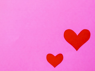 Red paper hearts on a pink paper background