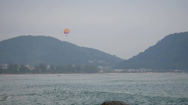 sea wave hit the rock shore seascape , Patong sand beach Phuket  parasail , tree and mountain are  background ,
