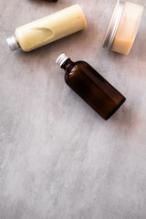 Bottles with spa cosmetic products from above on gray concrete table. Beauty blogger, salon treatments concept. Minimalism