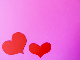 Red paper hearts on a pink paper background
