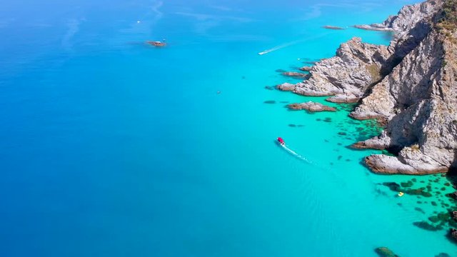 Aerial survey on colorful blue sea with rocky coast and boats going in Capo Vaticano Italy
