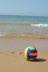 Obraz premium Ball on the sandy beach of sunny relaxing coastline, daytime seaside nature idyllic background