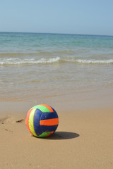 Obraz premium Ball on the sandy beach of sunny relaxing coastline, daytime seaside nature idyllic background