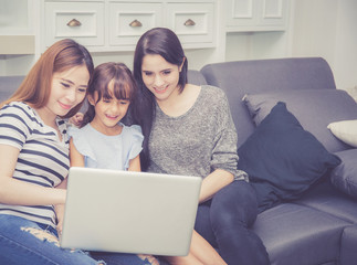 Mother, Aunt and kid having time together lerning with using laptop computer at home with relax and...