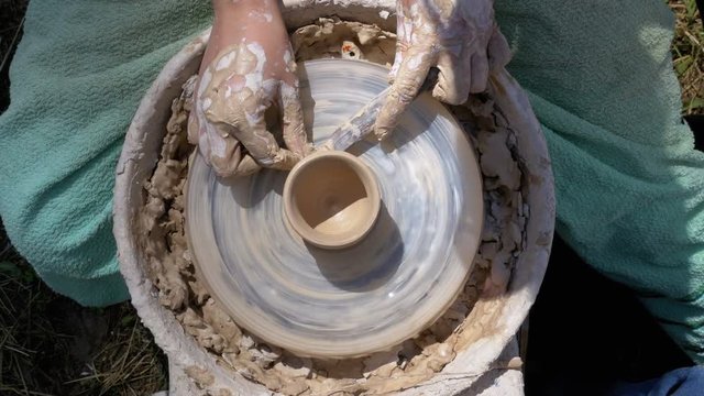 Hands of the Master Potter and Vase of Clay on the Potter's Wheel close-up. Master crock man. Twisted potter's wheel. Man creates a work of art. Master kneads the clay.