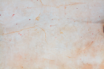 Light peach color of the wall. Background of antique color. Scratches and grain texture on the surface of the painted wall. Red drops and blots on white paint.