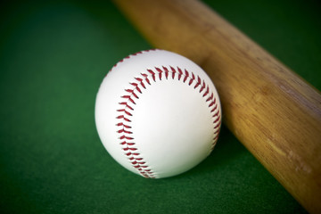 White Baseball ball and wooden bit isolated on green felt background