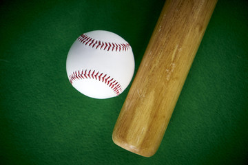 White Baseball ball and wooden bit isolated on green felt background