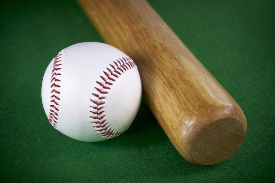 White Baseball ball and wooden bat isolated on green felt background