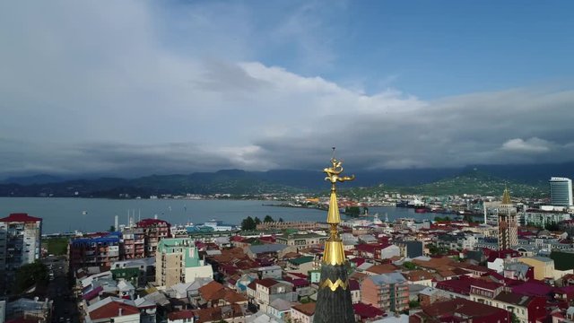Flying camera moves around the tower with an astronomical clock in the center of Batumi, in Europe square. Beautiful panoramic view of the city. Aerial view.