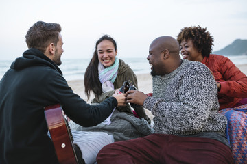 Diverse friends drinking beers at the beach