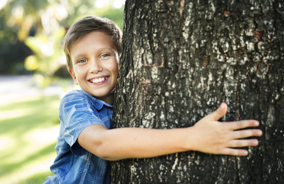 Boy hugging a big tree in the park